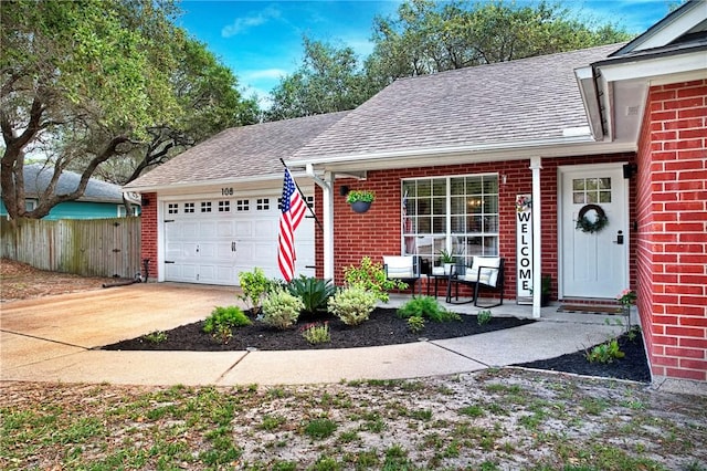 view of front of property featuring brick siding, an attached garage, fence, and roof with shingles