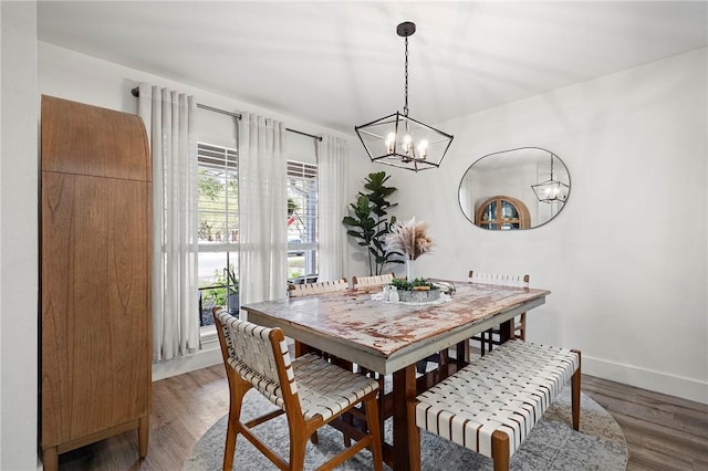 dining space with baseboards, a chandelier, and light wood-style flooring
