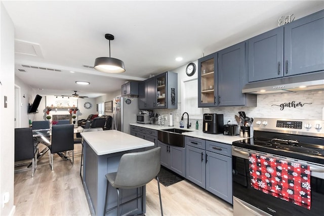 kitchen with sink, light hardwood / wood-style flooring, appliances with stainless steel finishes, pendant lighting, and decorative backsplash