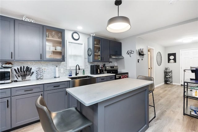 kitchen with a breakfast bar, decorative light fixtures, sink, a center island, and stainless steel appliances