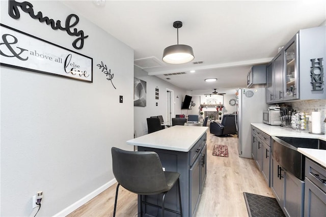 kitchen featuring a breakfast bar, hanging light fixtures, light wood-type flooring, stainless steel fridge, and a kitchen island