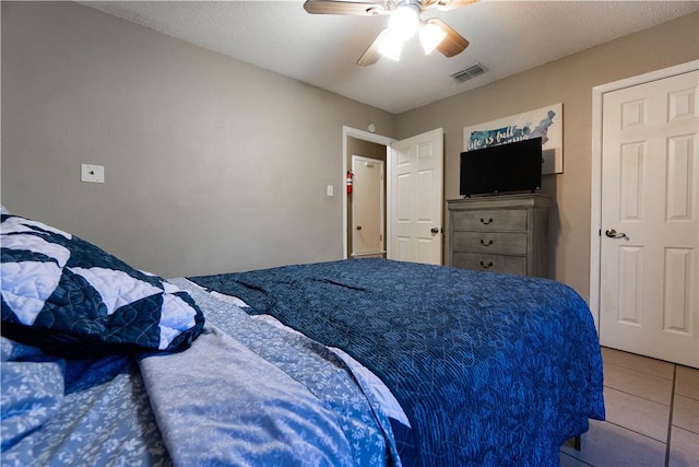 bedroom featuring ceiling fan, a textured ceiling, and light tile patterned floors