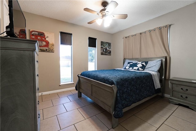 tiled bedroom with ceiling fan and a textured ceiling