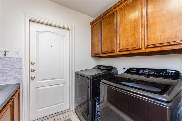 washroom featuring washer and dryer, light tile patterned floors, and cabinet space