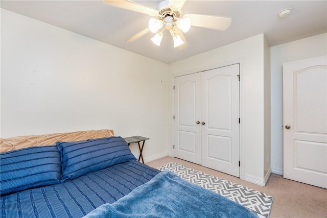 bedroom with a ceiling fan, light colored carpet, a closet, and baseboards