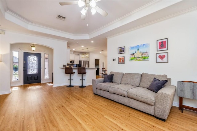 living area featuring a raised ceiling, light wood-style flooring, and visible vents