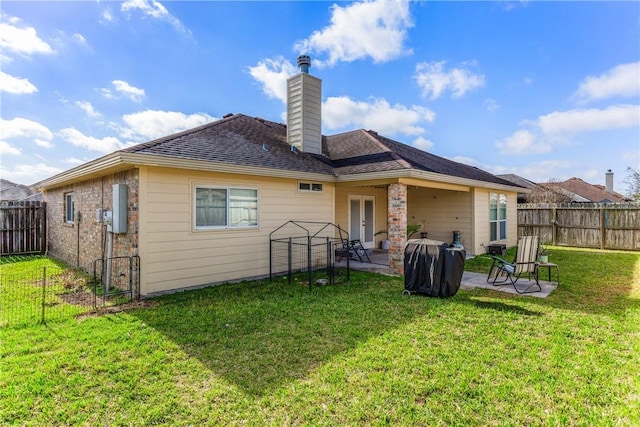 rear view of property with a lawn, french doors, a chimney, a fenced backyard, and a patio