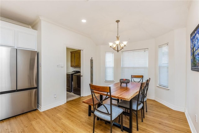 dining area with washing machine and dryer, baseboards, light wood finished floors, and a chandelier