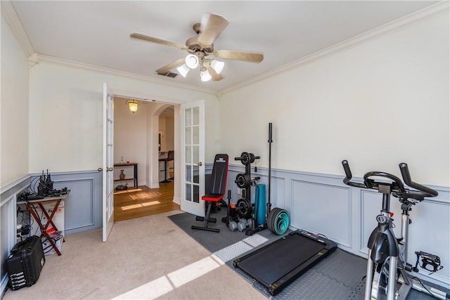 exercise area with carpet, arched walkways, french doors, wainscoting, and crown molding