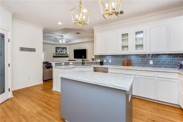 kitchen with tasteful backsplash, light wood-style flooring, a peninsula, and ornamental molding