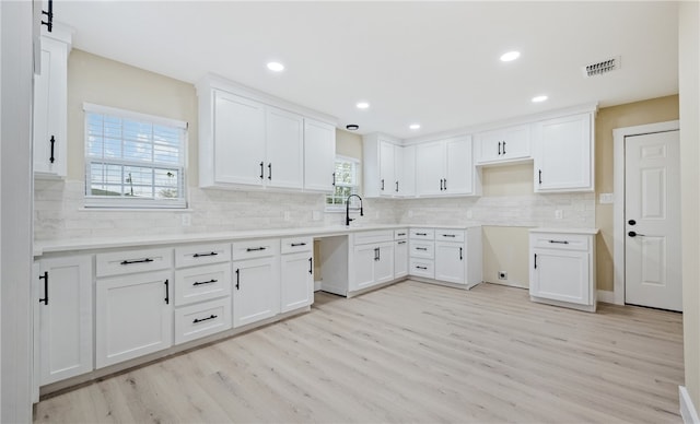 kitchen featuring tasteful backsplash, white cabinetry, sink, and light wood-type flooring