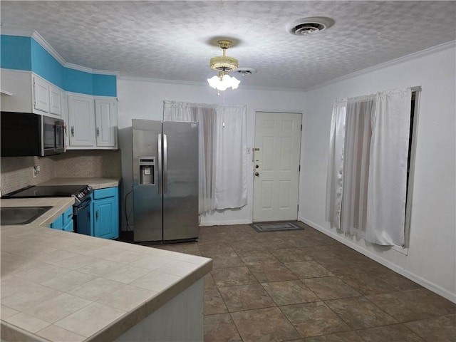 325 S Saunders St S, Aransas Pass, TX 78336 - kitchen with blue cabinets, tasteful backsplash, tile counters, stainless steel appliances, and white cabinetry