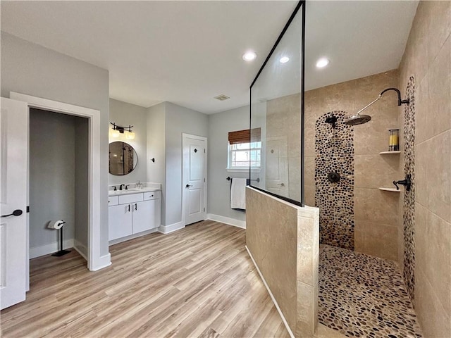 bathroom with vanity, wood-type flooring, and tiled shower