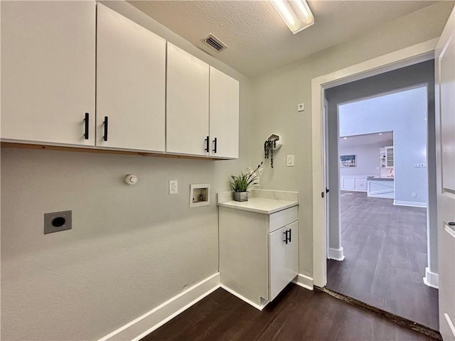 laundry room featuring electric dryer hookup, cabinets, hookup for a washing machine, a textured ceiling, and dark hardwood / wood-style flooring