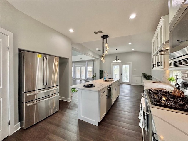 kitchen with white cabinetry, french doors, an island with sink, vaulted ceiling, and appliances with stainless steel finishes