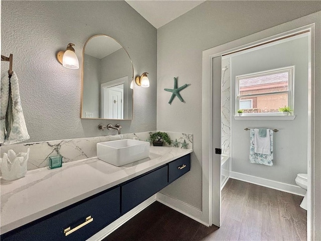 bathroom featuring wood-type flooring, vanity, toilet, and a tub