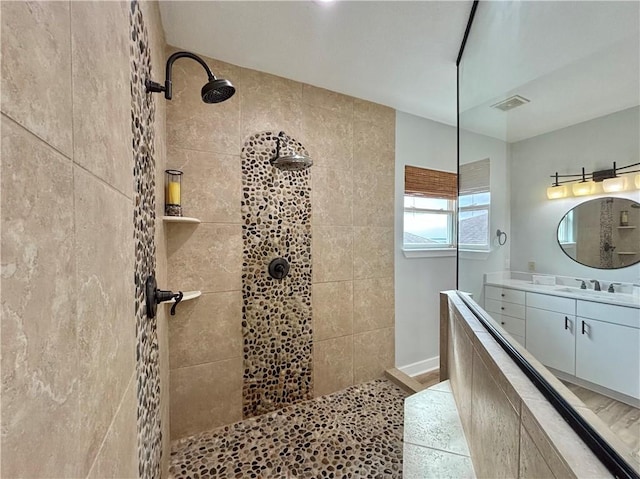 bathroom featuring tile patterned flooring, a tile shower, and vanity