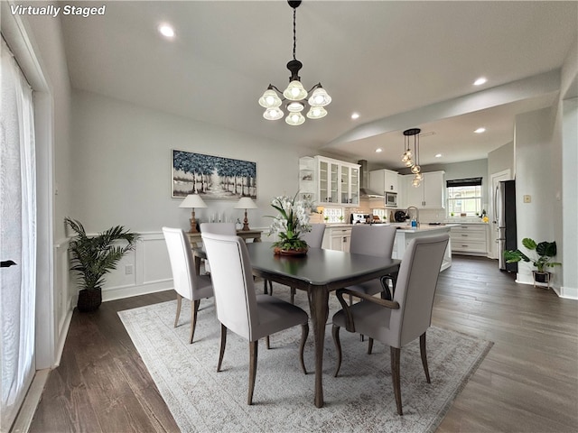 dining room featuring dark wood-type flooring, vaulted ceiling, and a notable chandelier