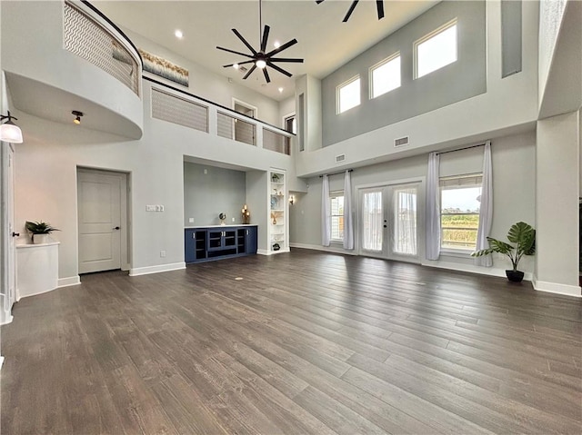 unfurnished living room with french doors, ceiling fan, hardwood / wood-style floors, and a high ceiling