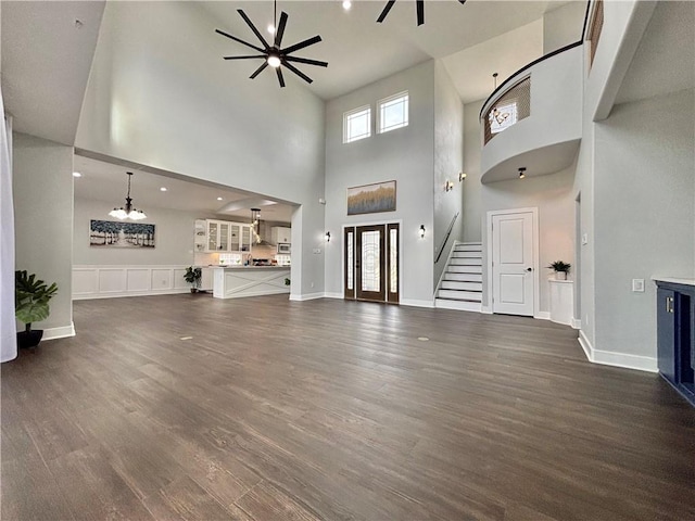 unfurnished living room with ceiling fan, dark hardwood / wood-style flooring, and a towering ceiling