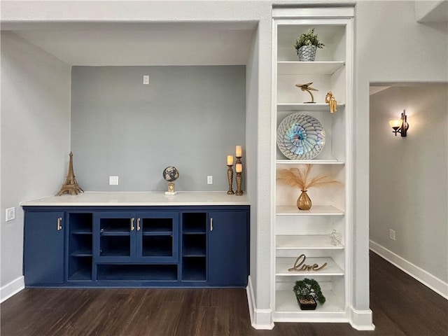 bar featuring dark hardwood / wood-style floors and blue cabinets