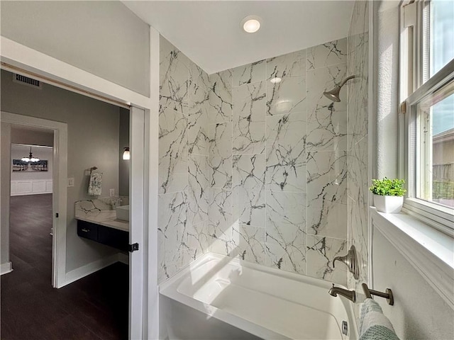 bathroom with vanity, wood-type flooring, and tiled shower / bath