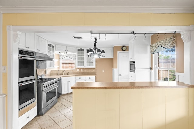 4410 Marie St, Corpus Christi, TX 78411 - kitchen featuring stainless steel appliances, a peninsula, under cabinet range hood, glass insert cabinets, and backsplash