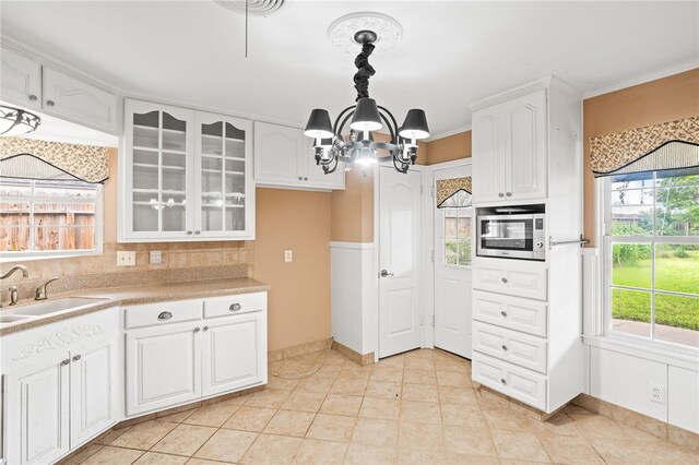 4410 Marie St, Corpus Christi, TX 78411 - kitchen featuring a chandelier, glass insert cabinets, light countertops, a sink, and white cabinets