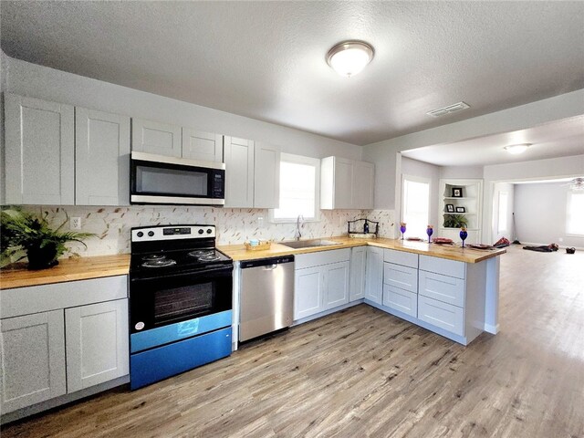 kitchen featuring sink, white cabinetry, wood counters, stainless steel dishwasher, and dark hardwood / wood-style floors