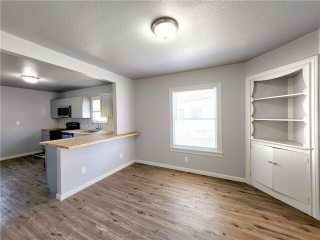 kitchen with wooden counters, white cabinets, stainless steel appliances, light wood-type flooring, and sink