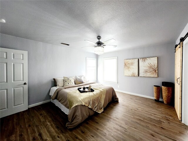 interior space with wood-type flooring, a textured ceiling, built in shelves, and a barn door