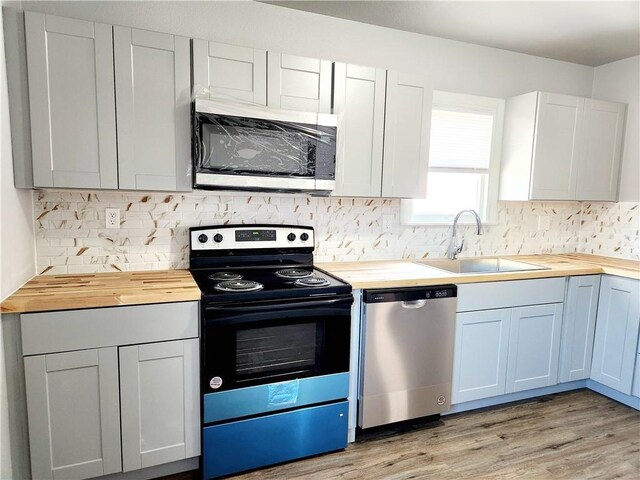 kitchen featuring sink, butcher block countertops, tasteful backsplash, and dark hardwood / wood-style floors