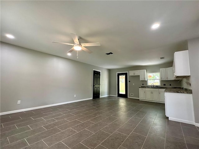 kitchen featuring dark countertops, ceiling fan, white cabinets, and baseboards