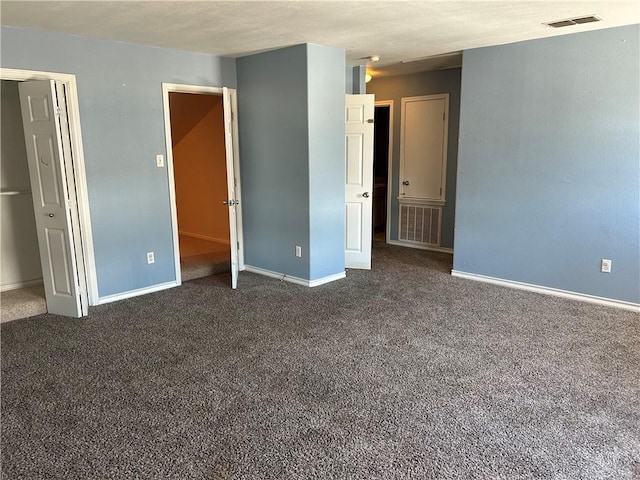 unfurnished bedroom featuring dark colored carpet, visible vents, and baseboards