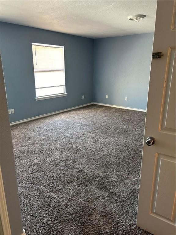 spare room with carpet floors, a textured ceiling, and baseboards