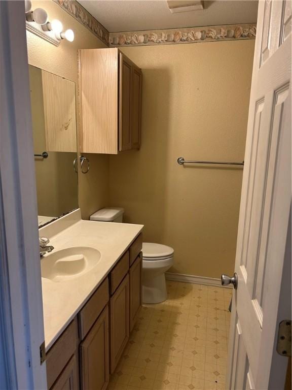 bathroom with toilet, tile patterned floors, baseboards, and vanity