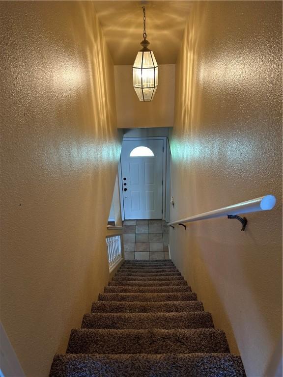 staircase with a textured wall and tile patterned floors