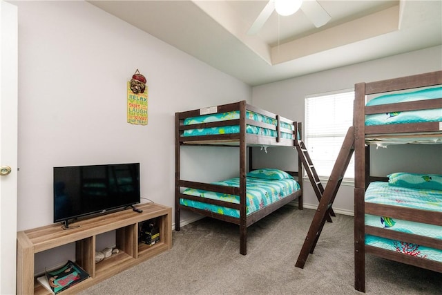 bedroom with ceiling fan, a raised ceiling, and carpet flooring