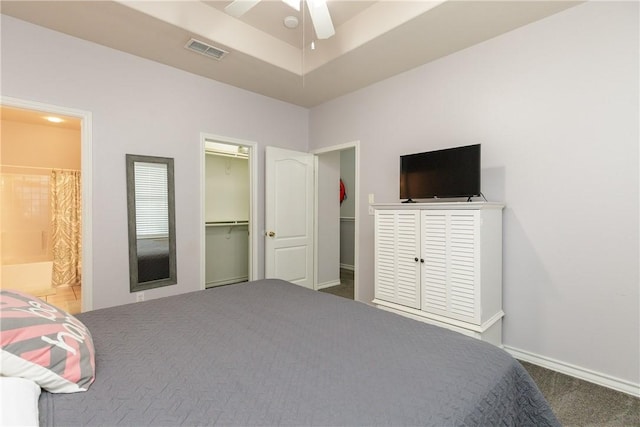 unfurnished bedroom featuring a spacious closet, connected bathroom, a closet, carpet flooring, and ceiling fan