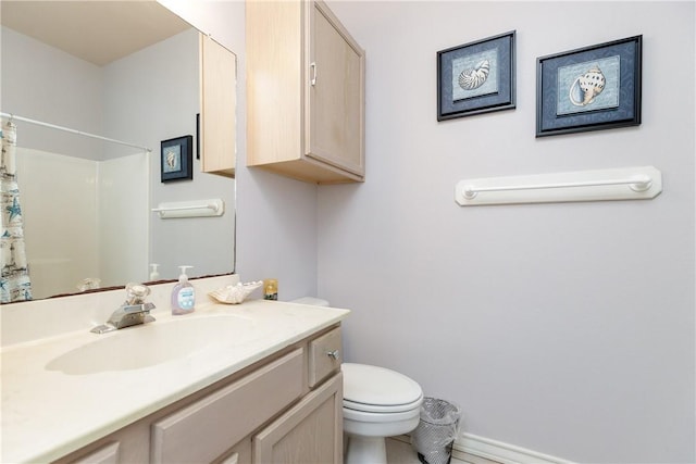 bathroom featuring toilet, vanity, and a shower