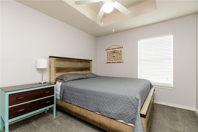 carpeted bedroom with a raised ceiling and ceiling fan