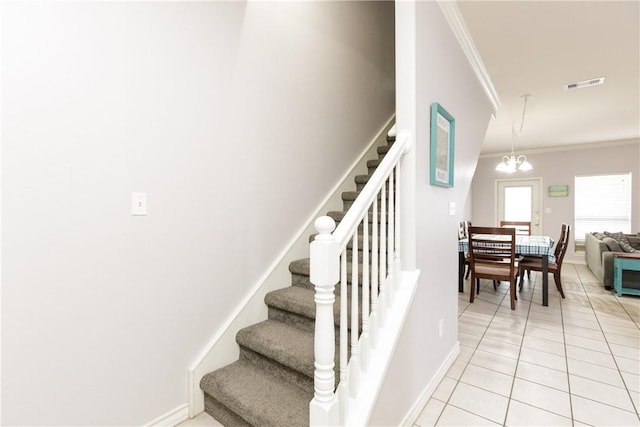 stairs with tile patterned floors, ornamental molding, and a notable chandelier