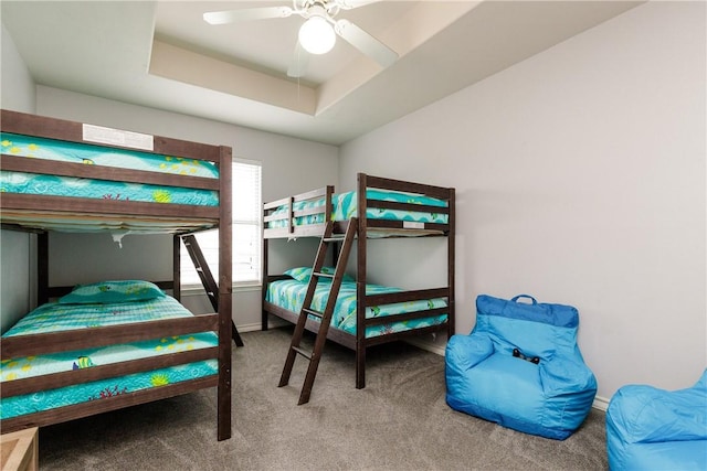 carpeted bedroom with ceiling fan and a raised ceiling