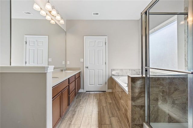 bathroom with a sink, double vanity, a shower stall, visible vents, and a garden tub