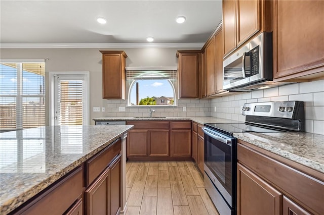 kitchen with crown molding, brown cabinets, appliances with stainless steel finishes, and a sink