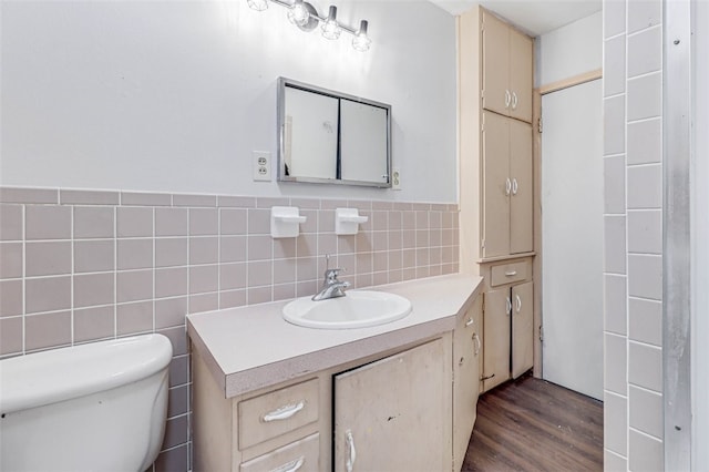 bathroom with wood-type flooring, toilet, vanity, and tile walls