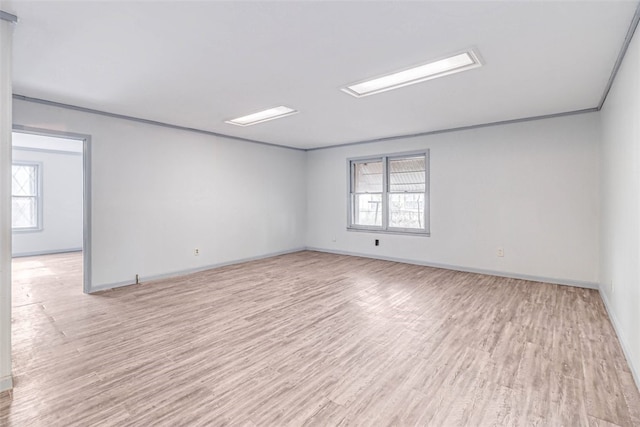 empty room with crown molding and light wood-type flooring