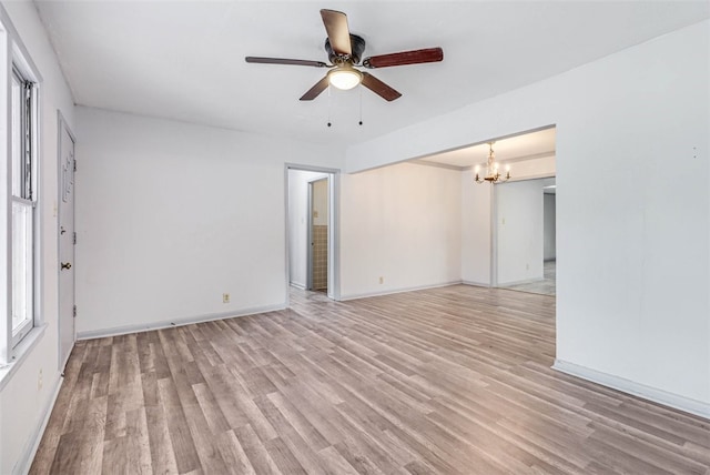 spare room with ceiling fan with notable chandelier and light hardwood / wood-style flooring