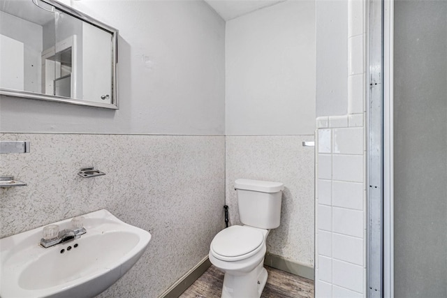 bathroom with hardwood / wood-style flooring, sink, tile walls, and toilet