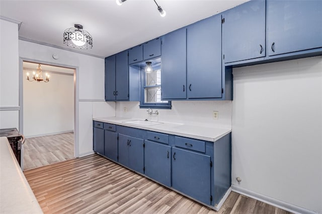 kitchen with hardwood / wood-style floors, blue cabinetry, a notable chandelier, decorative light fixtures, and sink